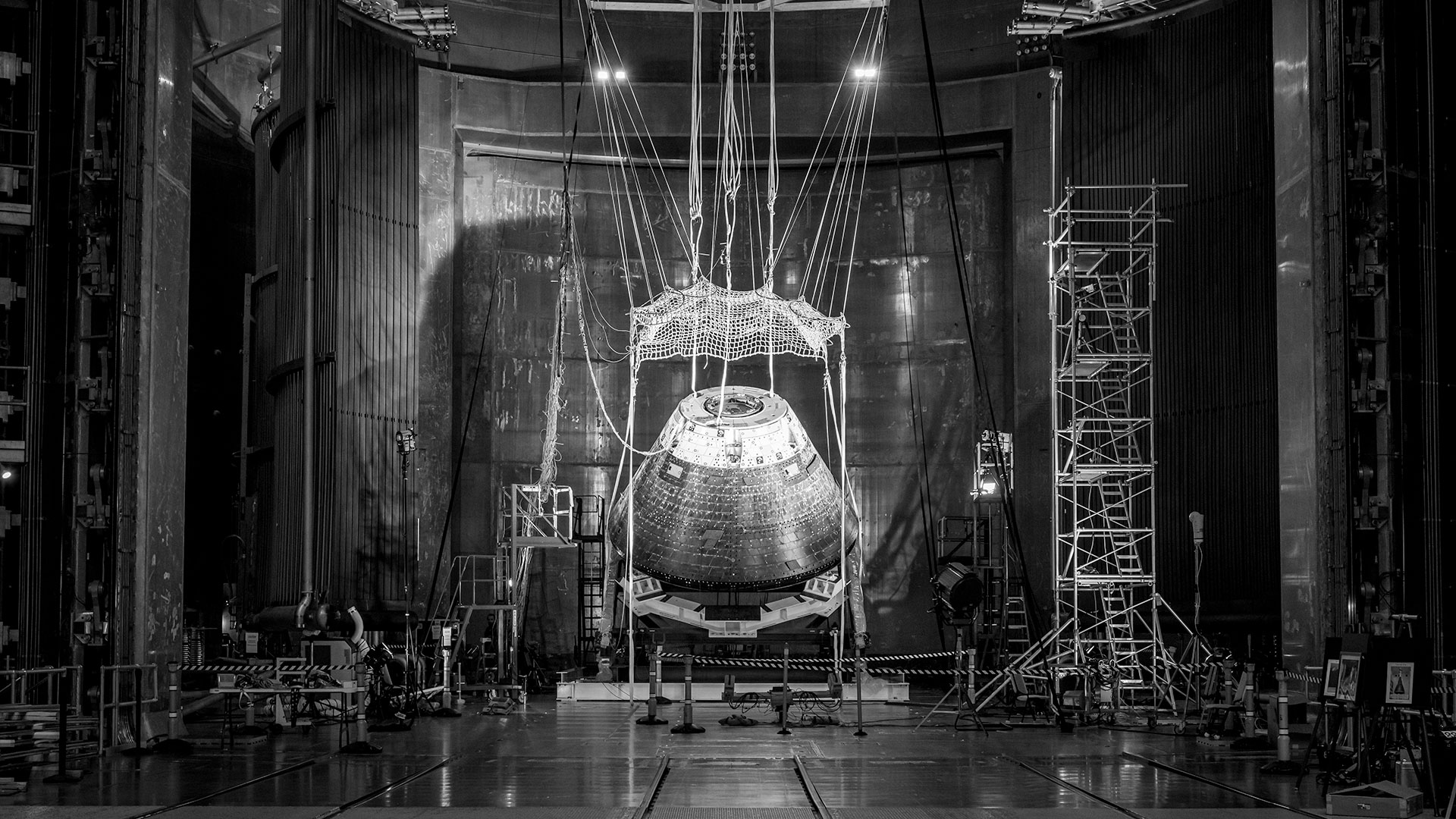a black and white photo of a space capsule being tested in a large chamber